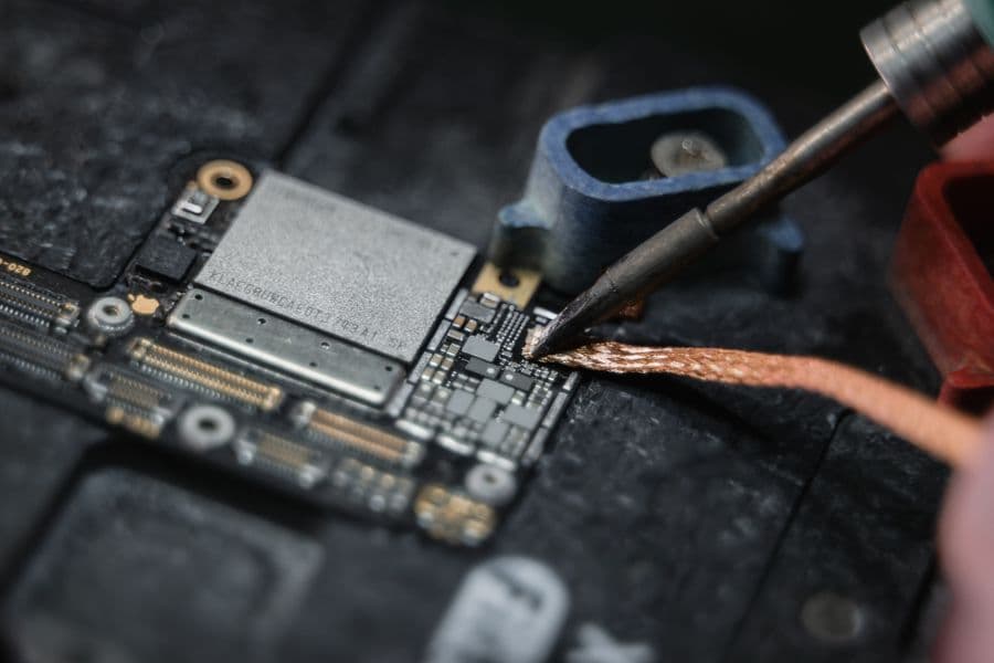 Detailaufnahme einer Smartphone-Platine bei der Reparatur mit einem Lötkolben