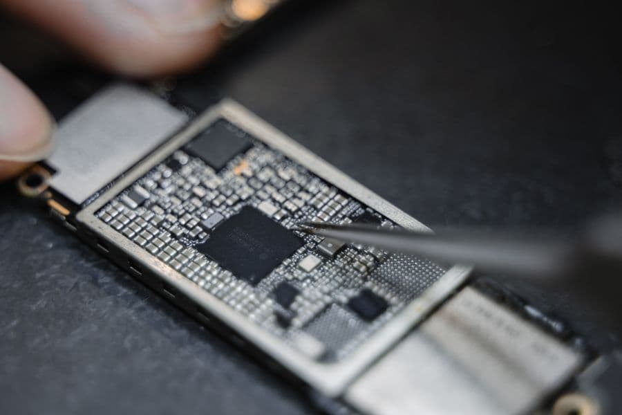 Feinarbeit mit einer Pinzette an einer Smartphone-Platine